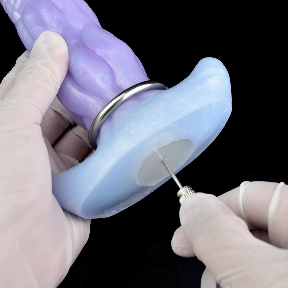 Light blue ovipositor dildo with metal ring, held near a purple egg-shaped cap