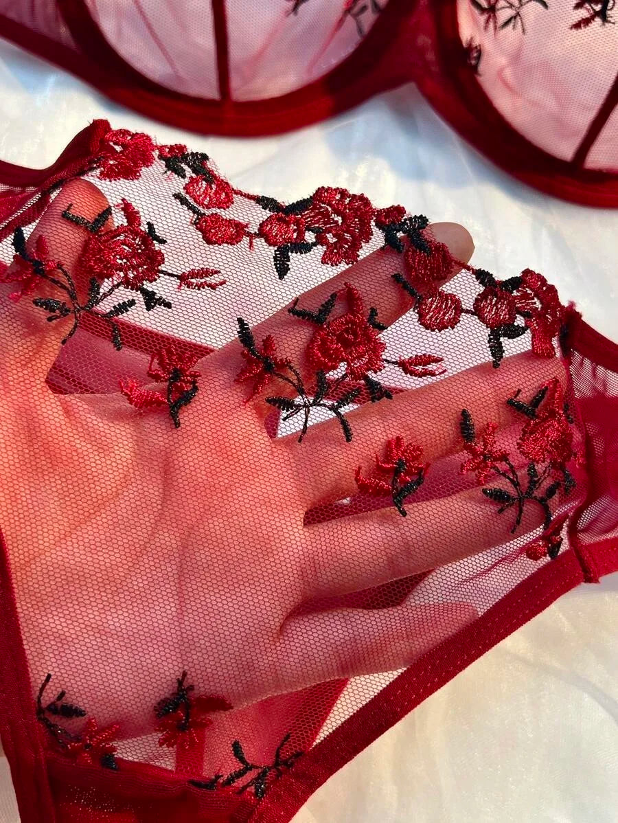 Close-up of red sheer lace fabric with floral embroidery on bra cup