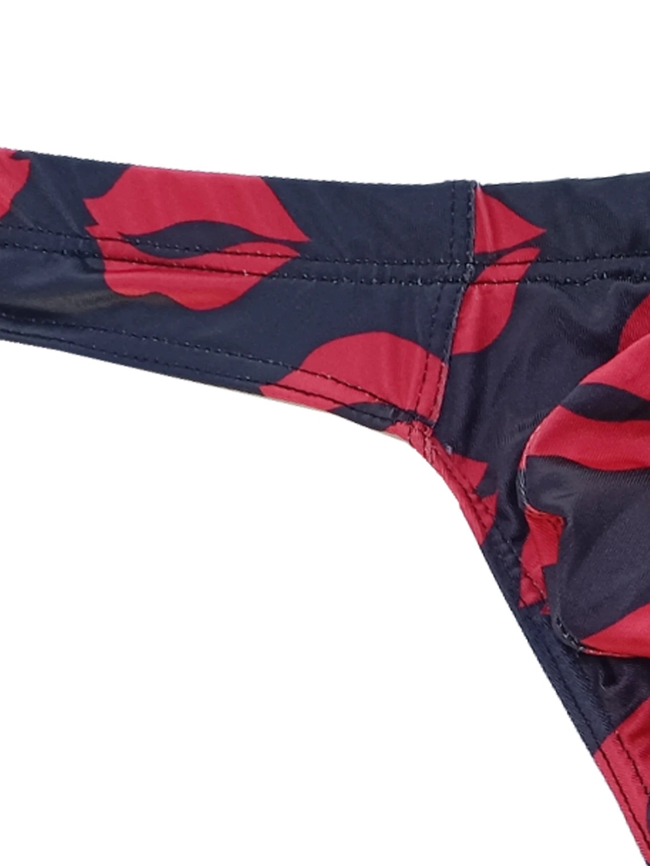 Close-up of dark navy low-rise thong waistband and leg opening with red lips print.