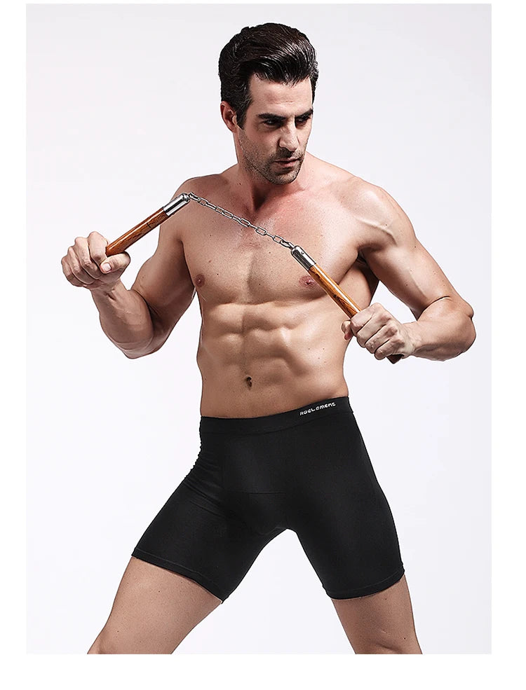 Black compression boxer briefs on model, mid-thigh length with elastic waistband