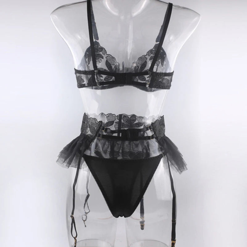 Black embroidered mesh lingerie set on mannequin: underwire bra, ruffle garter skirt, briefs and garters.