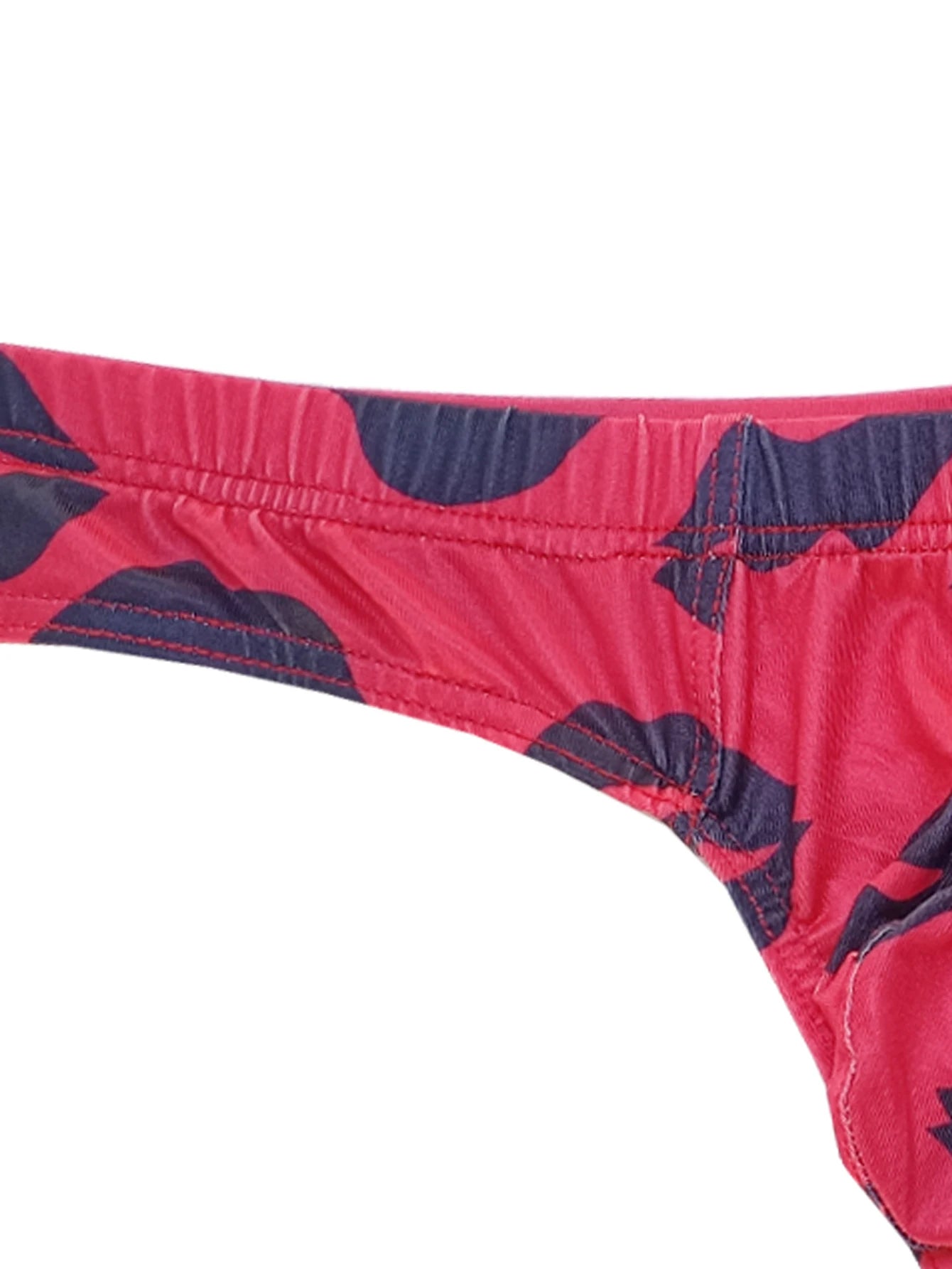 Close-up of red low-rise thong waistband with navy lips print and elastic stitching.