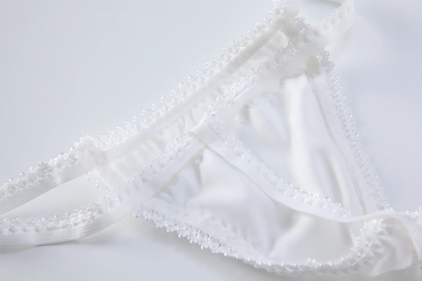 White lace-trim babydoll bodysuit with sheer ruffles and tie-neck front