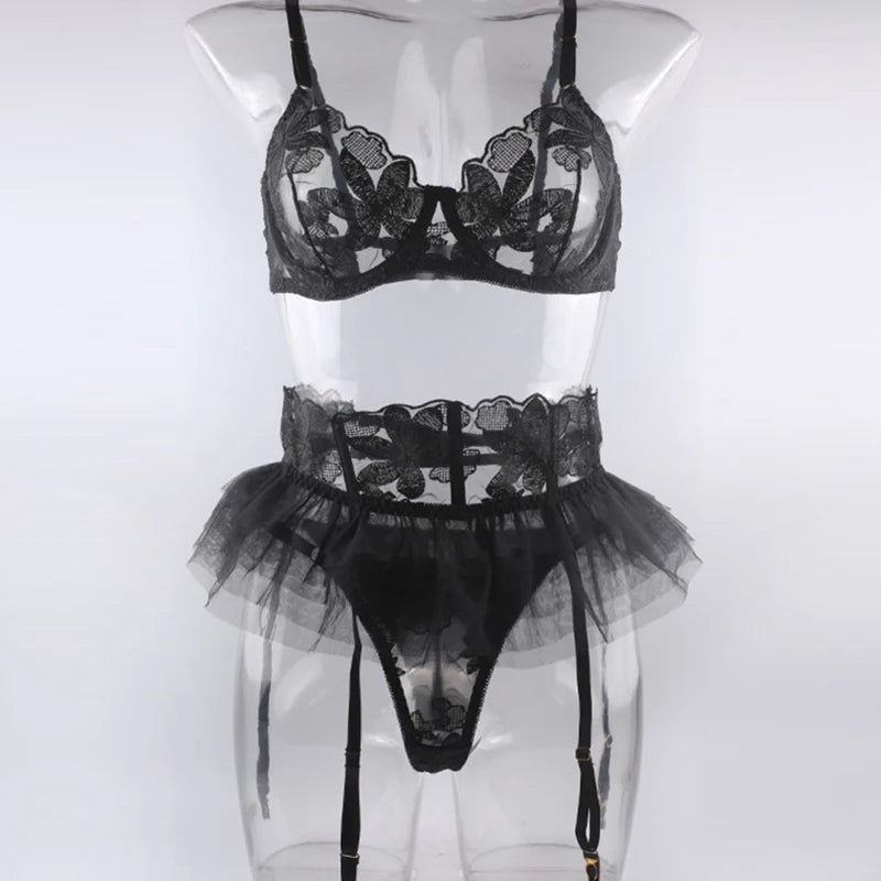 Black embroidered mesh lingerie set on mannequin: underwire bra, ruffle garter skirt, briefs.