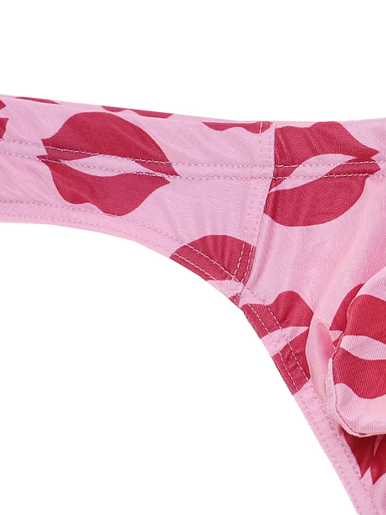 Close-up of light pink low-rise thong leg opening with red lips print and stitching.